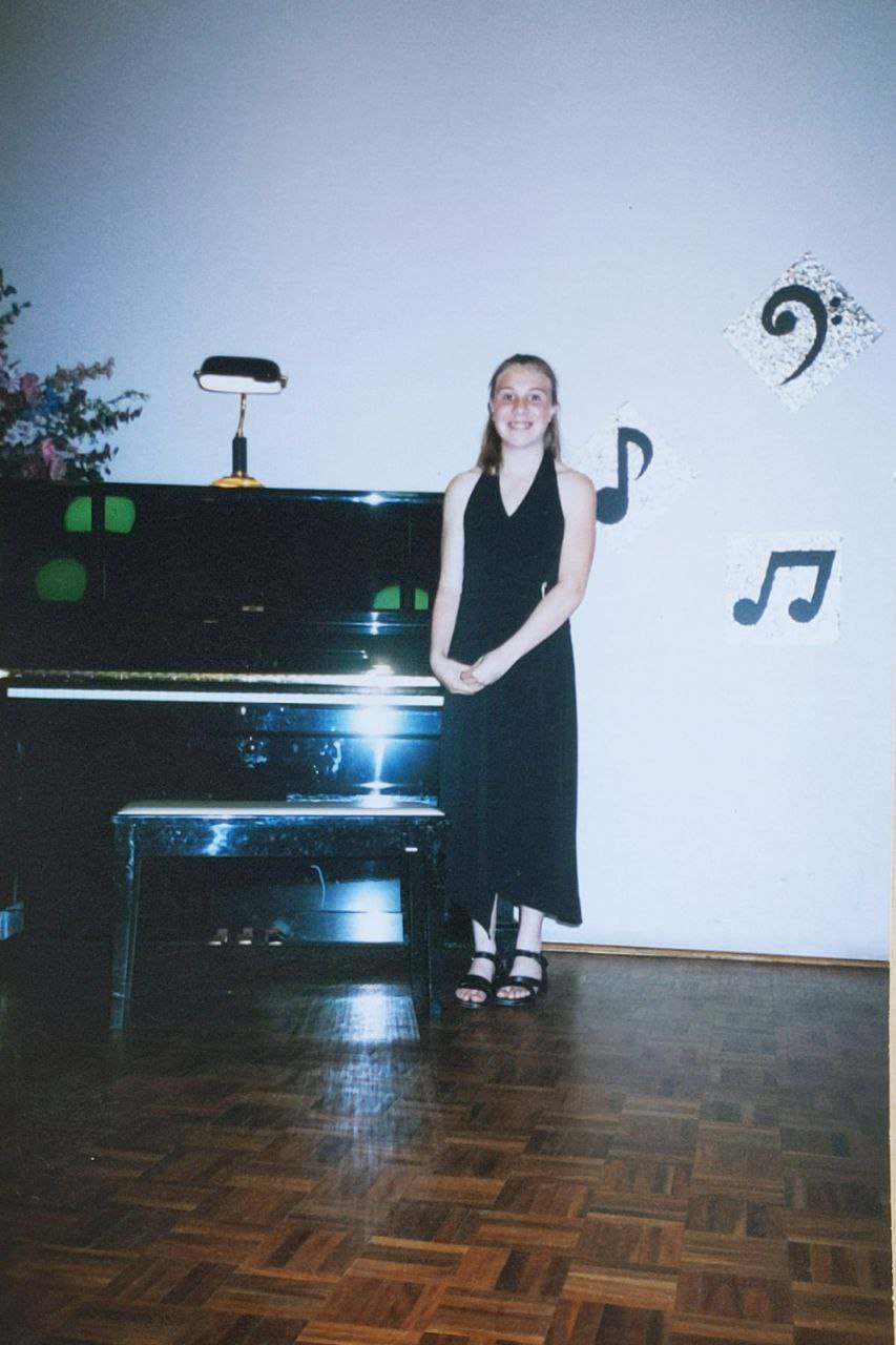 Bri standing next to a piano